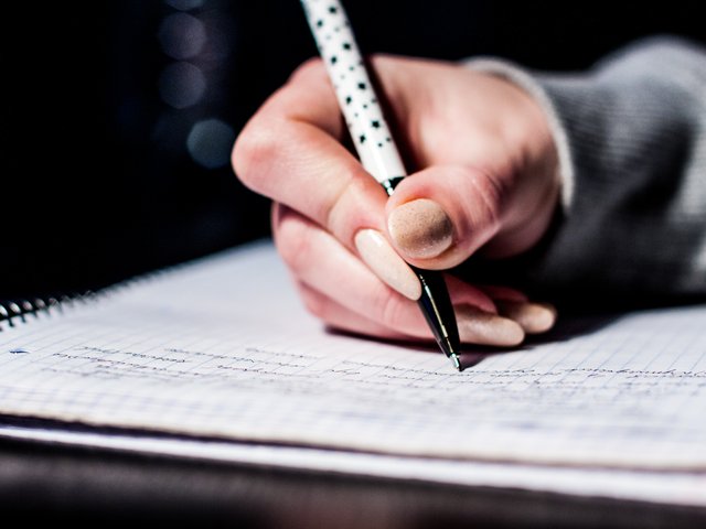 A student writing revision notes in a notebook